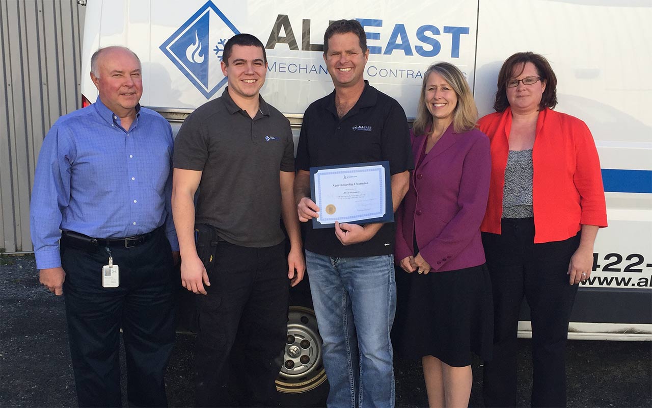 Employees of All East Mechanical gather around their Employer Champion award