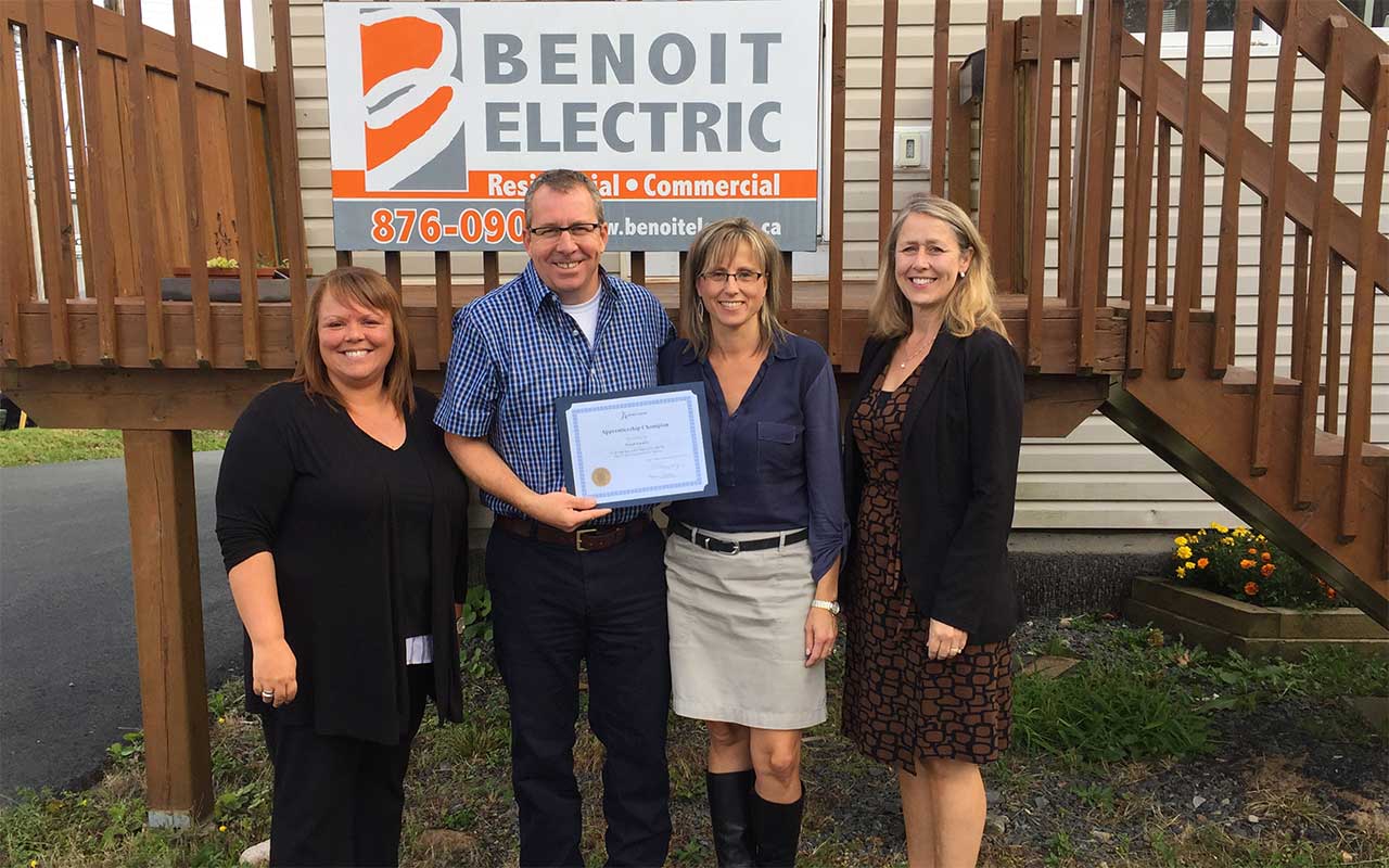 Employees of Benoit Electric gather around their Employer Champion award