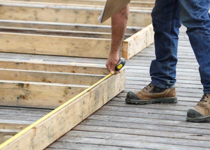 Carpenter measuring wood with measuring tape